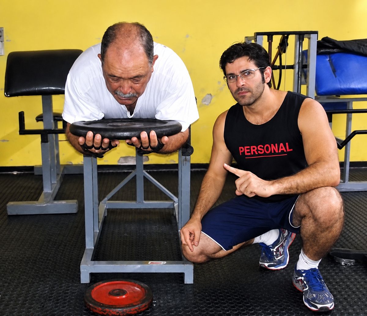 Eduardo acompanhando um aluno mais velho durante exercício para os braços